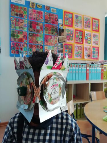 Criança com máscara tendo como fundo trabalhos que serviram de inspiração (Kandinsky)