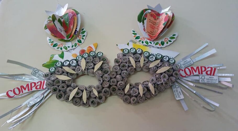 Aplicação de dois morangos e de outros elementos elaborados com recurso à reutilização de embalagens Compal/Tetra Pak para decoração da máscara.